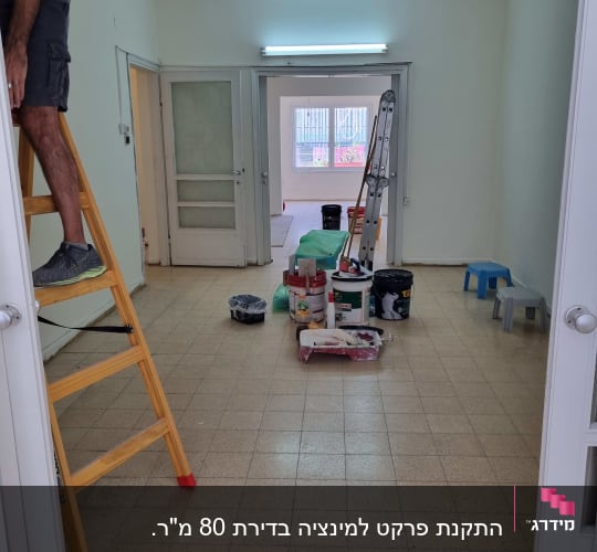 חדר עם רצפת פרקט, סולם, דלי צבע וכלי עבודה